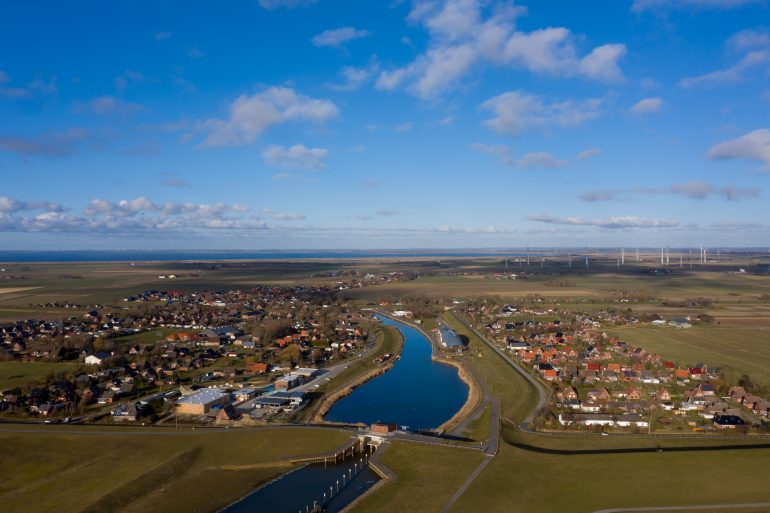 Luftaufnahme von Friedrichskoog Rugenort mit Blick auf den Ort das Rugenorter Loch und den alten Hafenstrom bis zur Nordseeküste, Schleswig Holstein, Deutschland